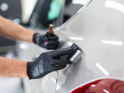 Car detailing - Man applies nano protective coating to the car. Selective focus.